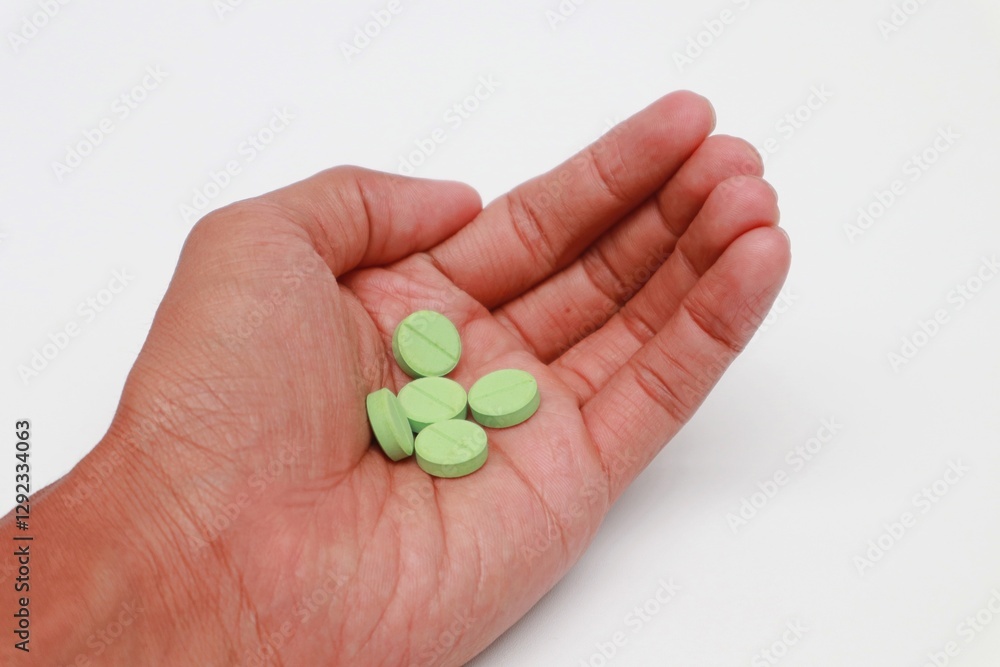 Hand holding Green Medicine Tablet on white background Hand holding Green Medicine Tablet on white background