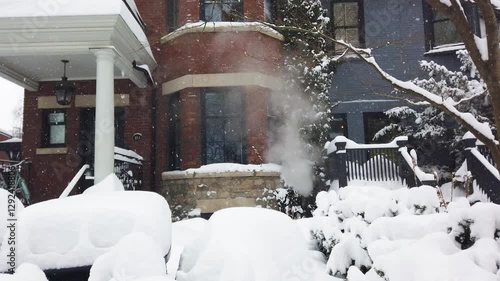 Wallpaper Mural Snowy winter in Toronto, Ontario, Canada. View of a two-story brick house with a porch and patio covered in snow. Steam from the heating system rises from the basement of the house. Torontodigital.ca