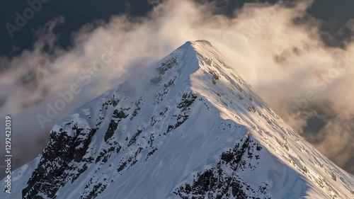 Snow-capped mountain peak with swirling clouds at sunrise, majestic and serene landscape. Adventure and exploration concept