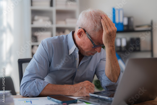 Bild auf Leinwand Senior businessman sitting at his office desk holding his head with his hand, sh