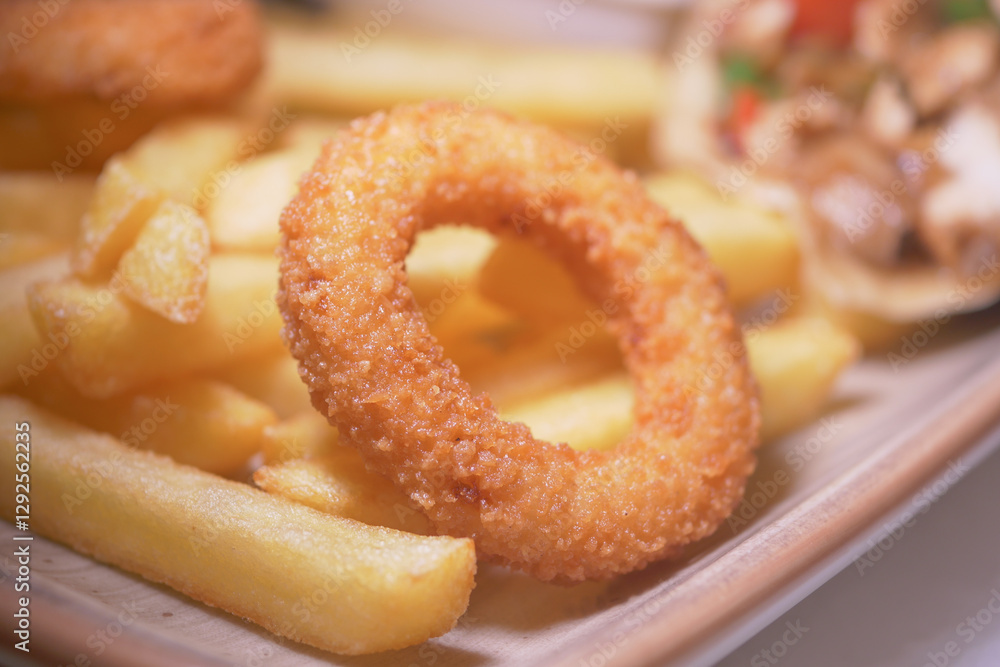 Crispy onion rings and golden fries served on a wooden plate Crispy onion rings and golden fries served on a wooden plate
