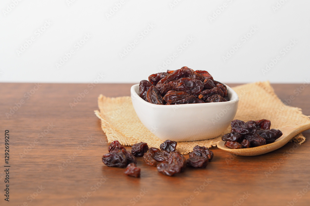 Raisins in white bowl on wooden table background. Dry raisins. Raisins in white bowl on wooden table background. Dry raisins.