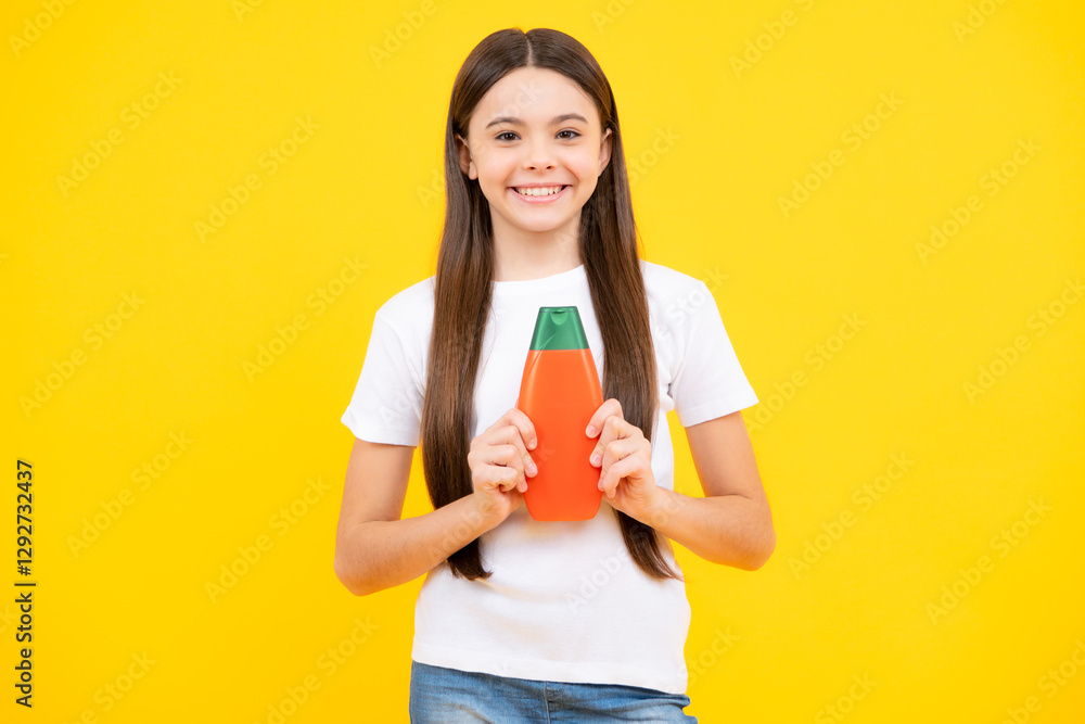 Teenager child girl showing bottle shampoo conditioners or shower gel isolated on yellow background. Hair cosmetic product. Mock up bottle. Happy teenager portrait. Smiling girl. Teenager child girl showing bottle shampoo conditioners or shower gel isolated on yellow background. Hair cosmetic product. Mock up bottle. Happy teenager portrait. Smiling girl.