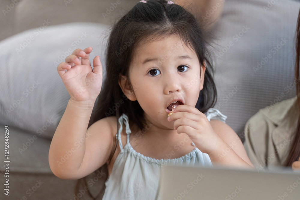 Child enjoying a snack while interacting with family Child enjoying a snack while interacting with family