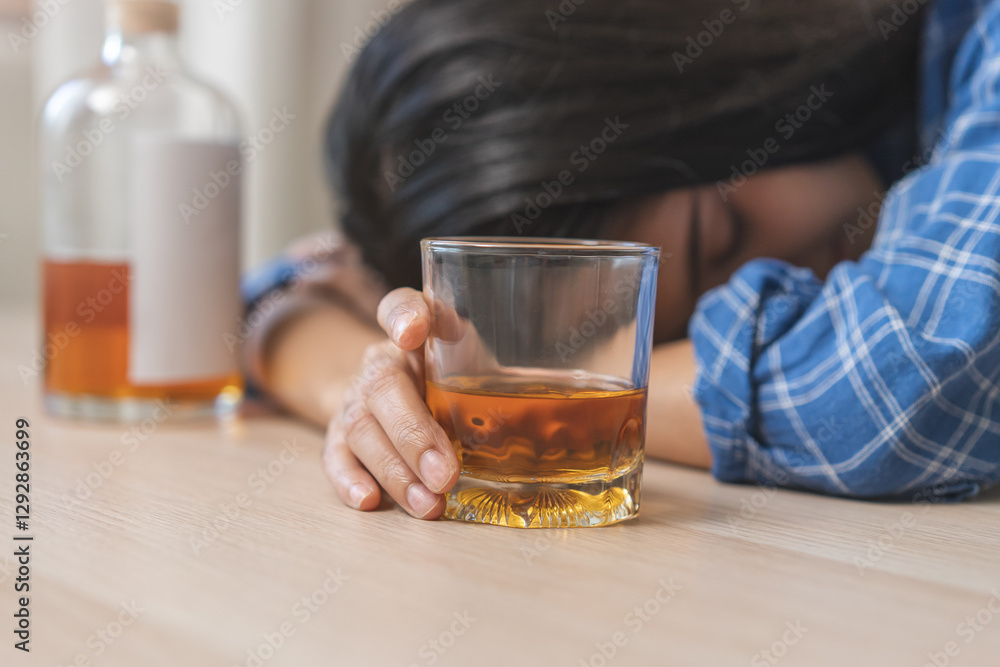 Alcoholism, depressed asian young woman fell asleep while drinking alcoholic beverage, hand holding glass of whiskey alone at night. Treatment of alcohol addiction, suffer abuse problem alcoholism. Alcoholism, depressed asian young woman fell asleep while drinking alcoholic beverage, hand holding glass of whiskey alone at night. Treatment of alcohol addiction, suffer abuse problem alcoholism.