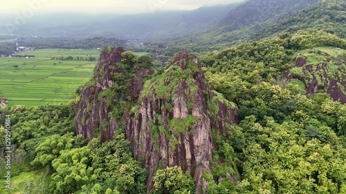 Aerial view of a towering rocky hill amidst lush green trees. View of Mount Sepikul, Sukoharjo, Indonesia. 4K drone scenery of Indonesia natural landscape. photo