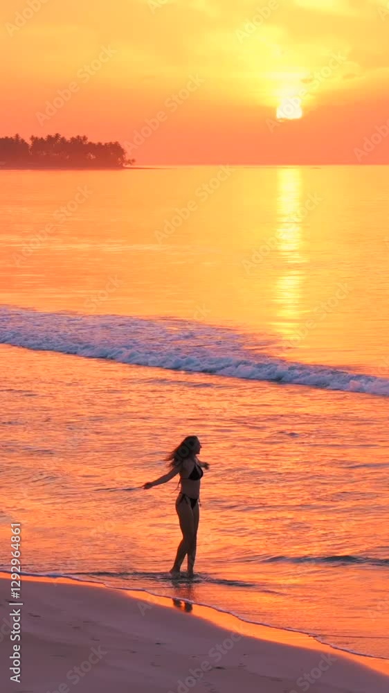 The silhouette of a pretty beautiful slender model girl in swimsuit running by the edge of water on the beach at amazing pink sunset. The silhouette of a pretty beautiful slender model girl in swimsuit running by the edge of water on the beach at amazing pink sunset.