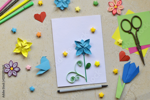 Crafting Handmade Greeting Card Featuring Origami, Quilling. Creative DIY Craft Workspace with Paper Birds, Hearts, Flowers, Decorative Stars and Stationery Tools Arranged 