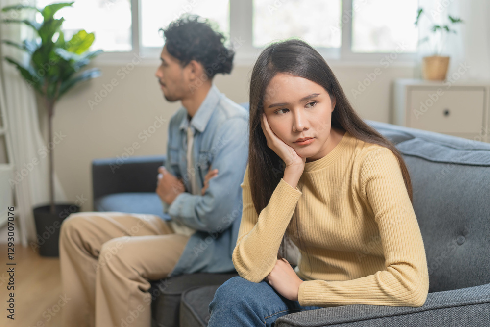 Family problem concept. Tension in relationship between married couple, husband and wife staying sitting separate after quarrel in the living room. Family problem concept. Tension in relationship between married couple, husband and wife staying sitting separate after quarrel in the living room.
