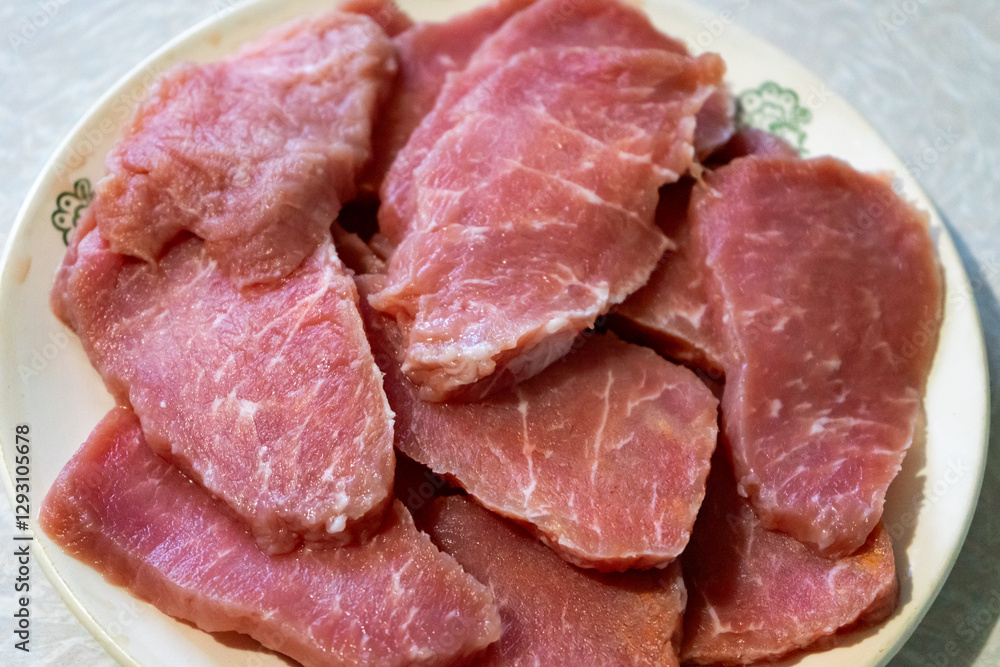 Freshly sliced pork on a plate ready for cooking Freshly sliced pork on a plate ready for cooking