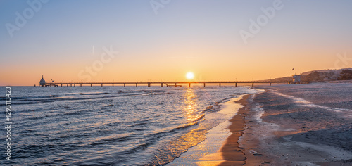 orangener Sonnenaufgang über der Seebrücke des Ostseebades Zinnowitz auf Usedom im Winter
