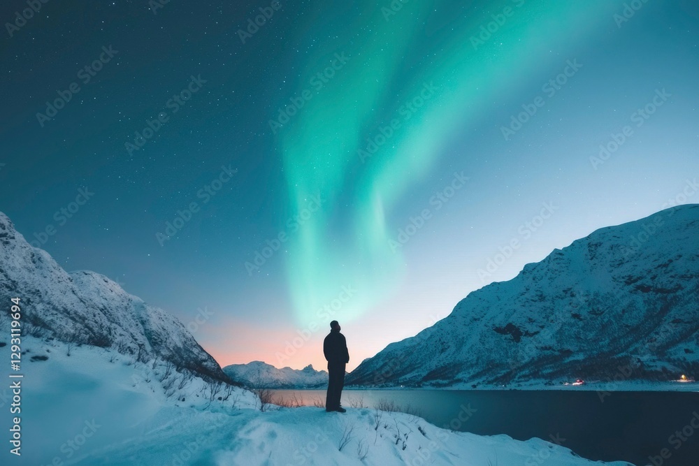 Fototapeta premium Person watching Northern Lights over snowy fjord mountains