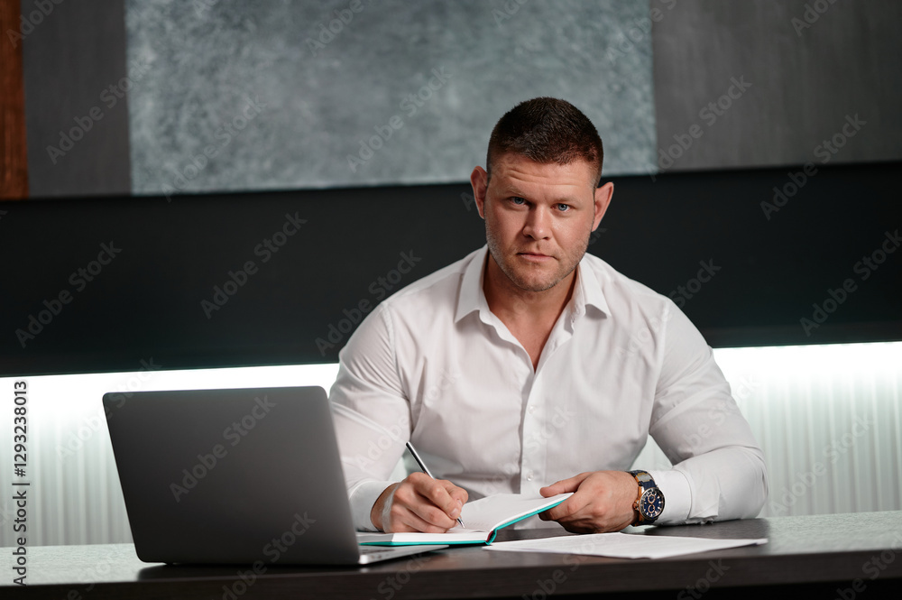 Young businessman is making notes in a notebook sitting in a cubicle at a desk. Business dress, successful business, manager. Young businessman is making notes in a notebook sitting in a cubicle at a desk. Business dress, successful business, manager.