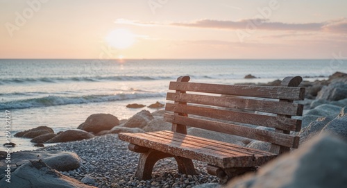 Sunset casting warm hues over a wooden bench along a rocky coastline in peaceful solitude.