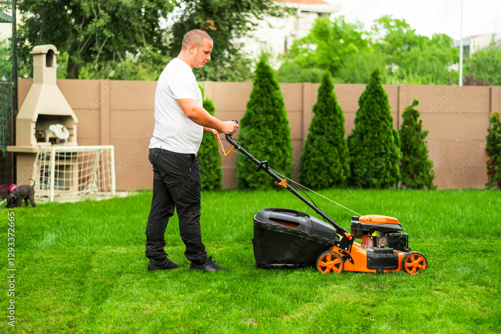 Gardener mowing grass with orange lawn mower in backyard garden Gardener mowing grass with orange lawn mower in backyard garden