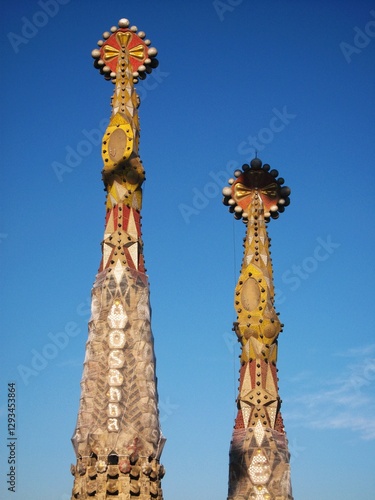 Close-up of two Sagrada Familia tower tops against clear blue sky. Architectural design details of Holy Family church towers. Detailed Sagrada Familia ornate spires. Landmark of Barcelona, Spain