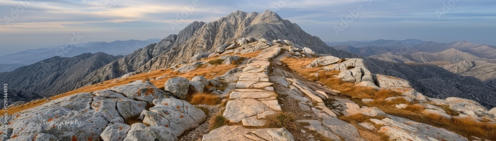 A scenic mountain path leads to a majestic peak, surrounded by rocky terrain and distant hills under a serene sky. A scenic mountain path leads to a majestic peak, surrounded by rocky terrain and distant hills under a serene sky.