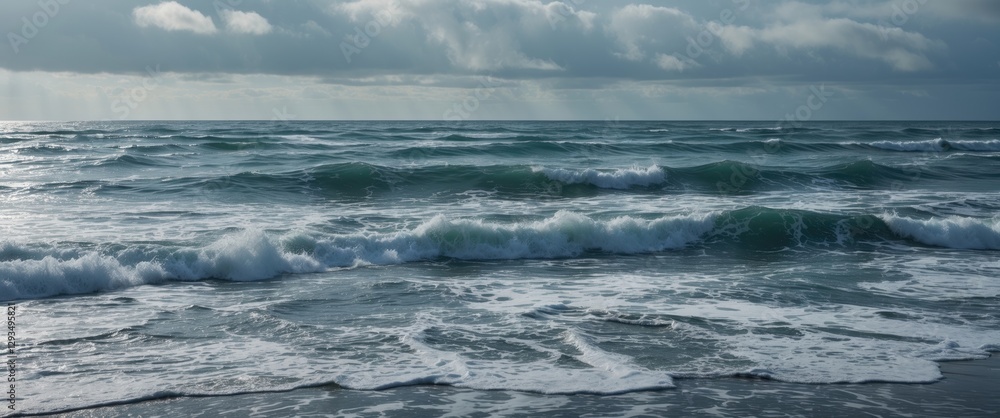 Fototapeta premium Waves crashing on a shoreline under cloudy summer skies with empty space for text, evoking serenity and tranquility by the sea.