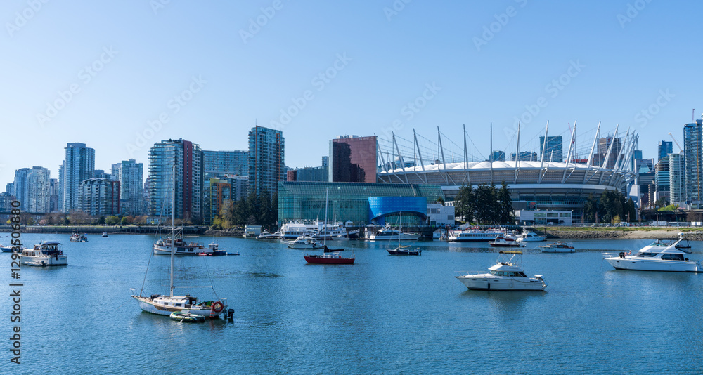 Vancouver, BC, Canada - April 16 2021 : Vancouver marina, False Creek, modern buildings skyline in the background. BC Place. Vancouver, BC, Canada - April 16 2021 : Vancouver marina, False Creek, modern buildings skyline in the background. BC Place.