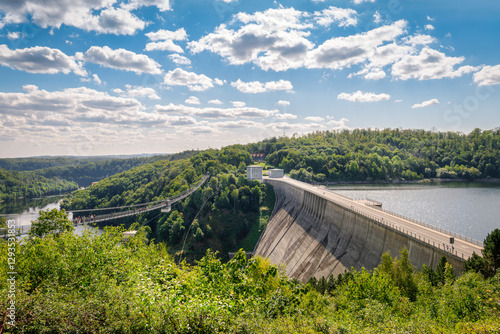 Rappbode Valley, Germany  – August 26, 2024: Tourists visit the Titan RT Suspension bridge and Rappbode Dam (Harz Mountains, Saxony). The bridge spans the river Bode in the middle of the valley