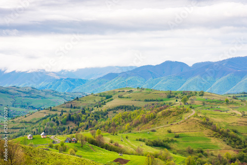 Obraz na płótnie mountainous rural landscape in spring. climate carpathian. trees and agricultural fields on hills rolling in to the distant valley. ridge beneath a overcast sky in dappled light. outdoor adventure w salonie