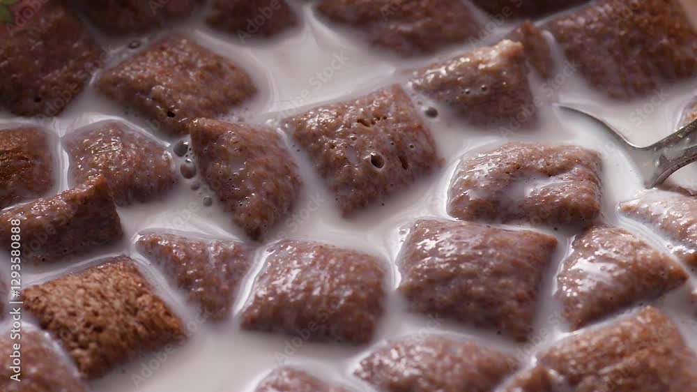 breakfast of milk and chocolate cereal pillows macro , falling chocolate pillows in plate with spoon and milk slow motion , spoon stir milk sweet breakfast breakfast of milk and chocolate cereal pillows macro , falling chocolate pillows in plate with spoon and milk slow motion , spoon stir milk sweet breakfast