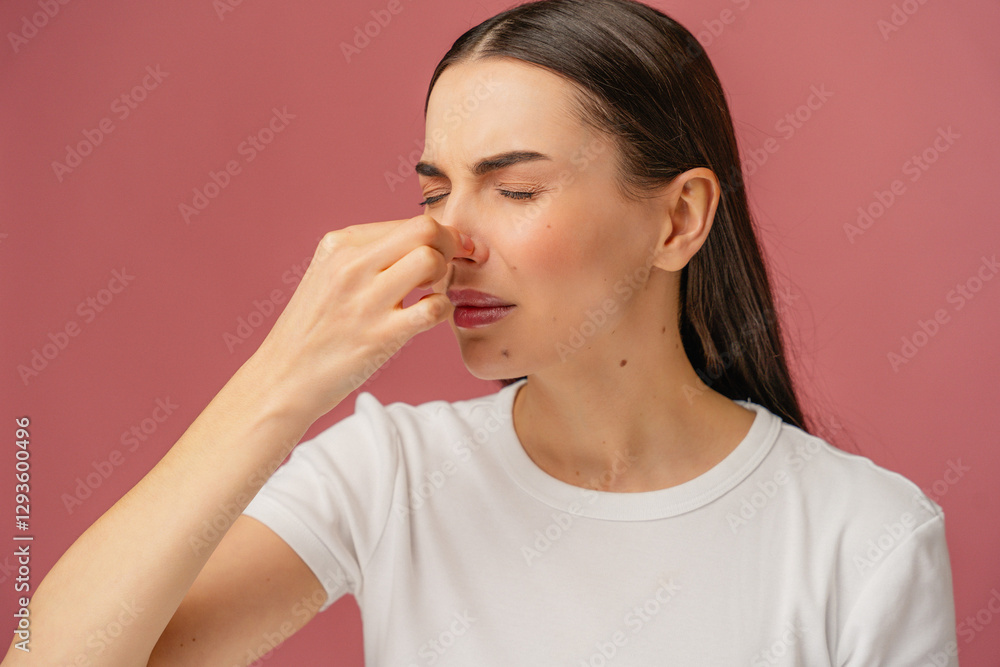 Person in white shirt pinching nose, reacting to an unpleasant odor, studio shot. Person in white shirt pinching nose, reacting to an unpleasant odor, studio shot.