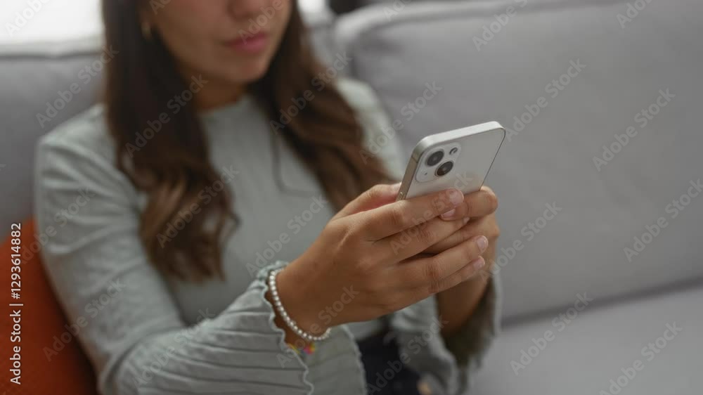 Woman using smartphone indoors with brunette hair in a cozy home setting, displaying focus and technology in a relaxed living room environment. Woman using smartphone indoors with brunette hair in a cozy home setting, displaying focus and technology in a relaxed living room environment.
