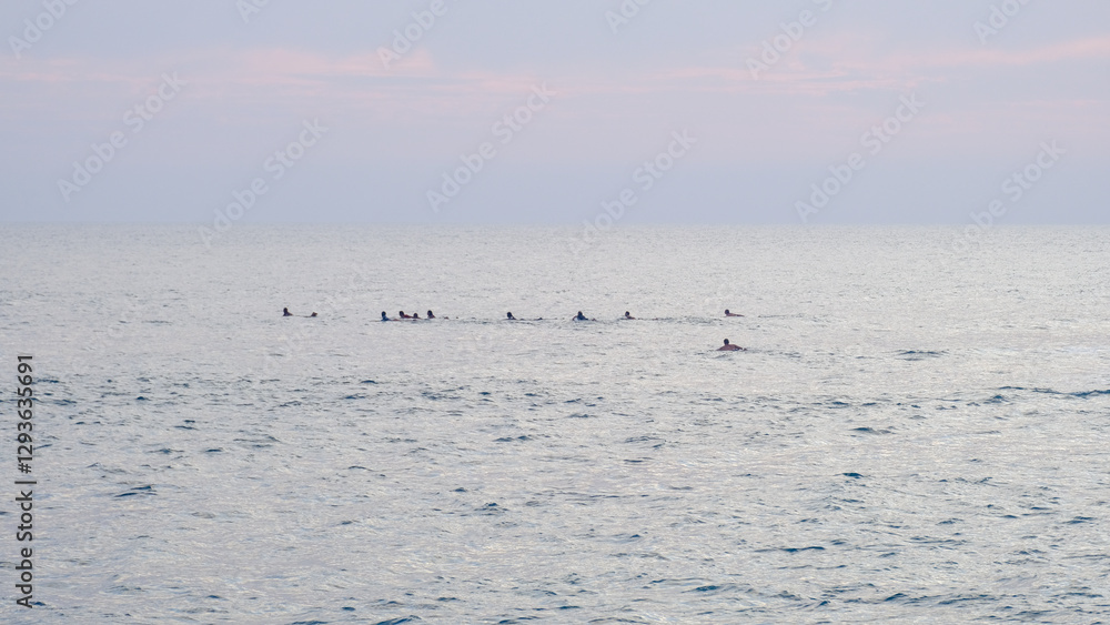Silhouetted surfers waiting for a wave in ocean during sunset in Midigama on South Coast of Sri Lanka Silhouetted surfers waiting for a wave in ocean during sunset in Midigama on South Coast of Sri Lanka