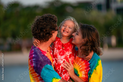 Photography Family enjoys joyful moment on beach during sunset wearing colorful tie-dye shir