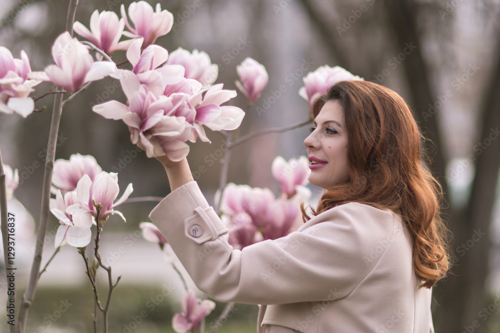 Fototapeta premium Woman magnolia flowers, surrounded by blossoming trees., hair down, wearing a light coat. Captured during spring, showcasing natural beauty and seasonal change.
