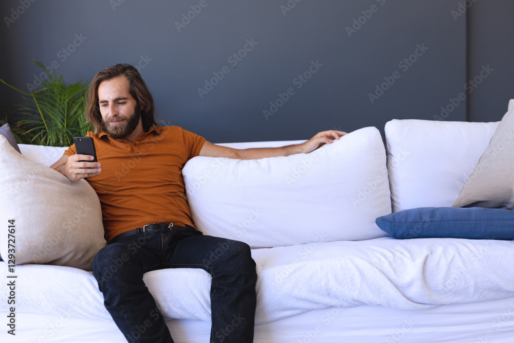 Relaxing on sofa, man using smartphone at home, enjoying leisure time, copy space Relaxing on sofa, man using smartphone at home, enjoying leisure time, copy space