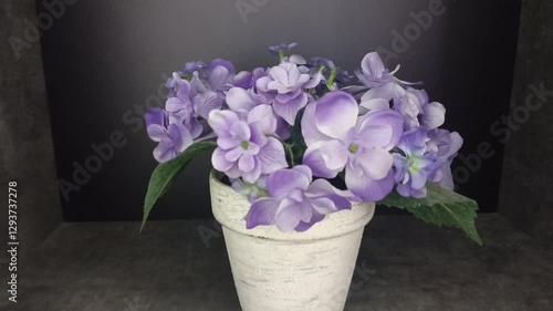 Beautiful light purple flowers are in a white vase on a slightly dark background