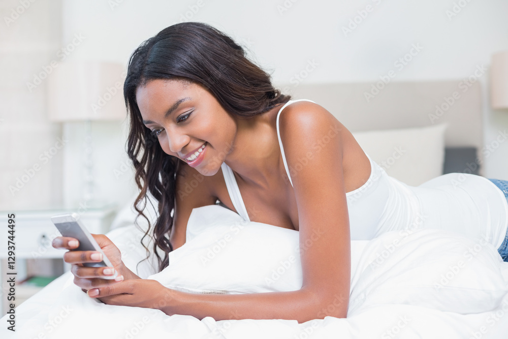 African American woman smiling while using smartphone in cozy bedroom African American woman smiling while using smartphone in cozy bedroom