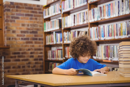 Foto Curly-haired boy reading book in library, surrounded by shelves of books