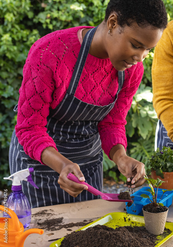 Woman gardening outdoors, planting seedlings with trowel, wearing striped apron photo