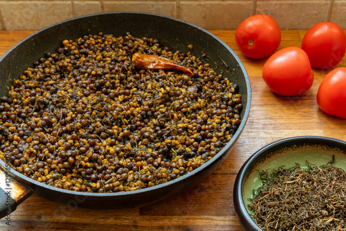 Methi Kerau (dried Nepalese green peas with fenugreek seeds and jimbu herb) on a frying pan. Dried aromatic jimbu herb in in a bowl on the side. photo