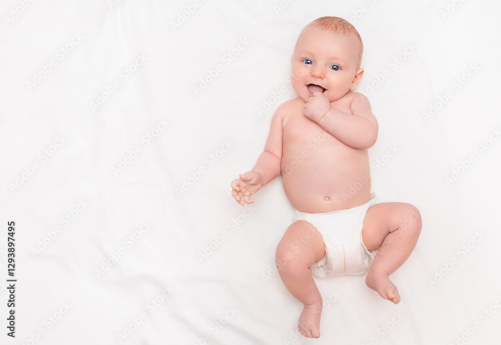 cute baby in diaper lying on back, smiling and holding hand in mouth cute baby in diaper lying on back, smiling and holding hand in mouth
