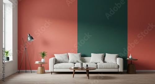 A minimalist living room features a white sofa against a twotoned coral and green wall. Wooden side tables, floor lamp, and plants complete the stylish setup.