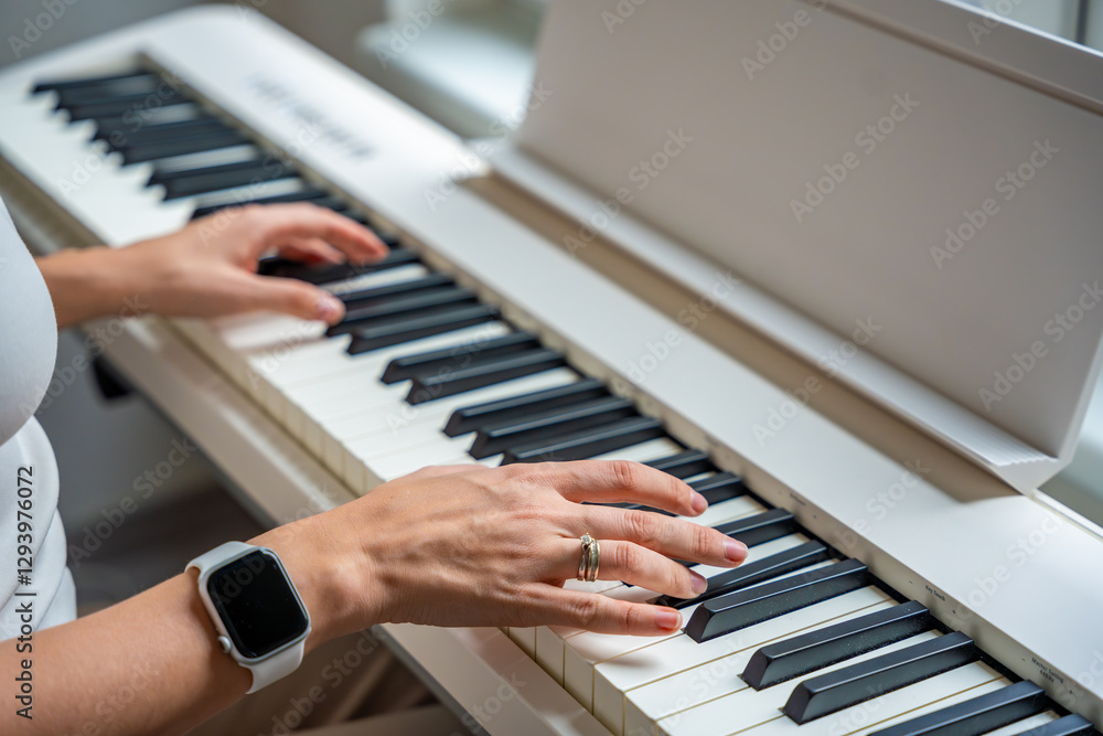Fototapeta premium Closeup woman's hand playing piano. Concept of home lesson of music: learning music enhances motor skills, hearing, and intelligence, fostering creativity