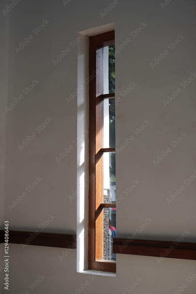 A long window with wooden lines against a white wall exposed to the morning sunlight A long window with wooden lines against a white wall exposed to the morning sunlight