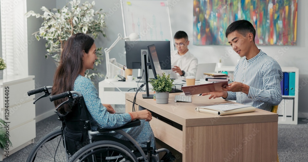 Fototapeta premium Woman is sitting in wheelchair at desk in office across employer they are signing employee contract man extends hand, they shake hands thanking each other for conversation congratulating