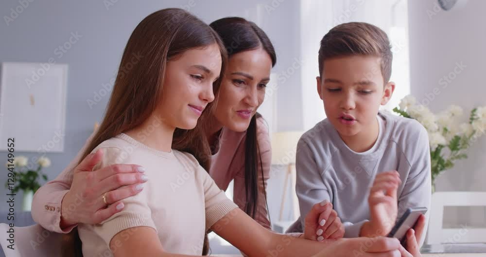 Positive family talking on video call via smartphone say hello to their father on distance wave hands in webcam enjoy online communication being at home. Family and technology concept Positive family talking on video call via smartphone say hello to their father on distance wave hands in webcam enjoy online communication being at home. Family and technology concept
