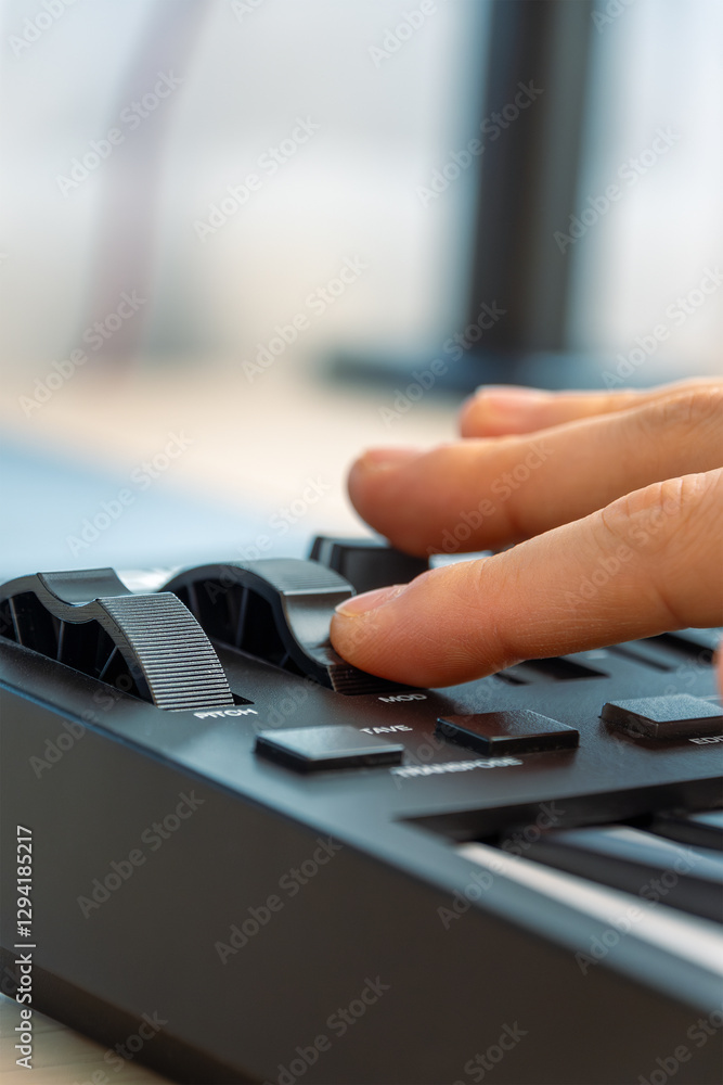 Woman playing MIDI keyboard with control knobs and pads, close-up. Woman playing MIDI keyboard with control knobs and pads, close-up.