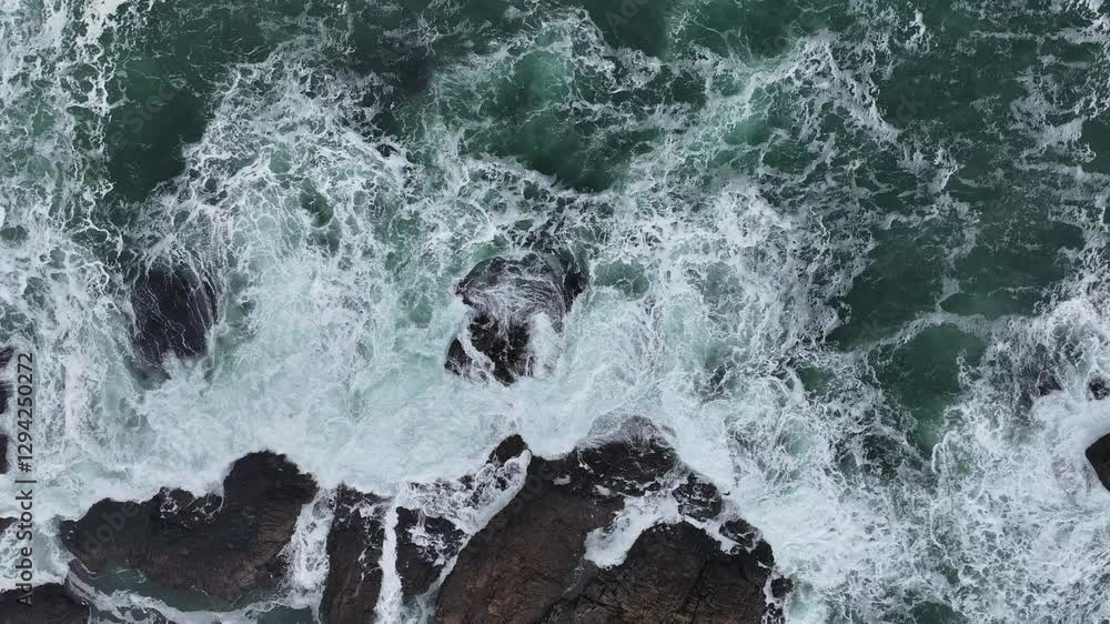 Aerial slow-motion showcasing the foamy waves from above, crashing a rocky shore Aerial slow-motion showcasing the foamy waves from above, crashing a rocky shore