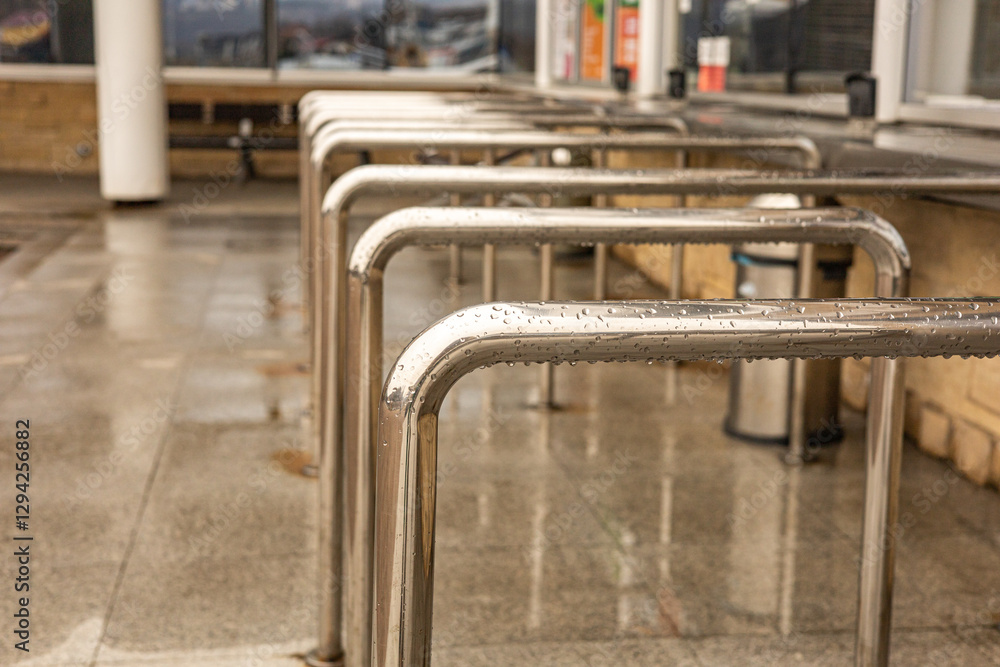 Row of metal railings used at ticket booths to keep lines organized and prevent people from cutting in. Queue management in public places. Visual boundary to stand and maintain order. Row of metal railings used at ticket booths to keep lines organized and prevent people from cutting in. Queue management in public places. Visual boundary to stand and maintain order.