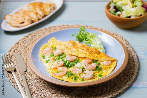Prawn omelette with green peas on blue plate. Eggs with shrimps