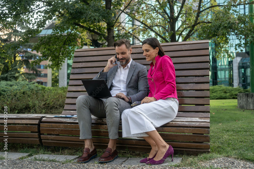 Fototapeta premium Business colleagues using laptop outside of office building.