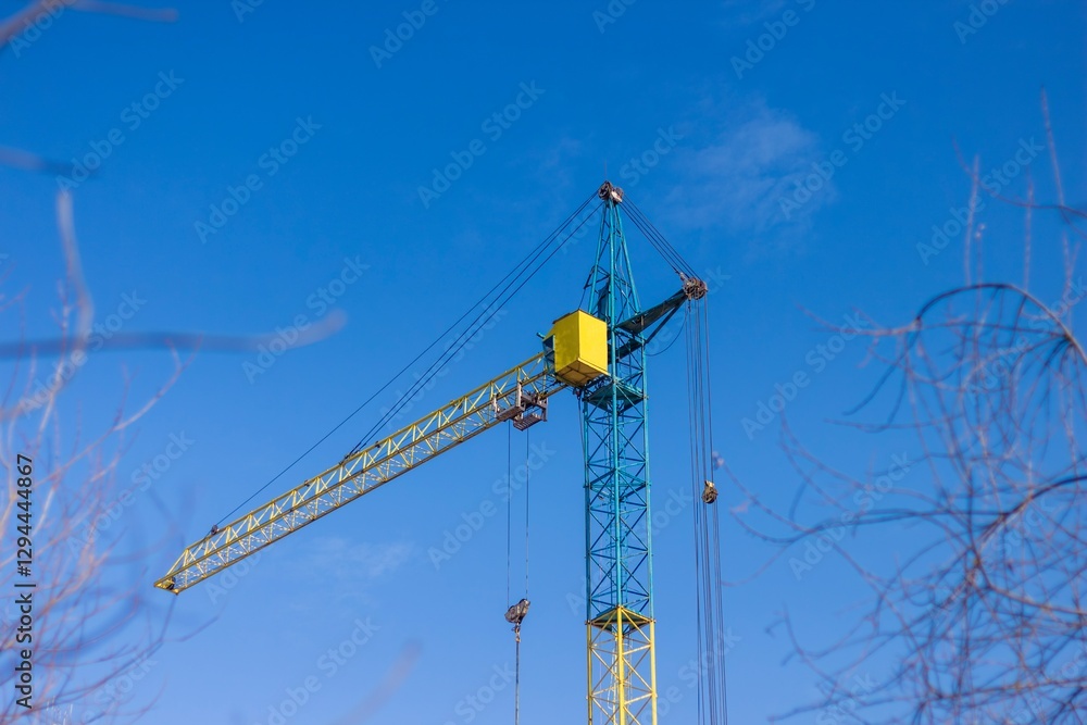 Construction crane towering against a clear blue sky during daylight hours Construction crane towering against a clear blue sky during daylight hours