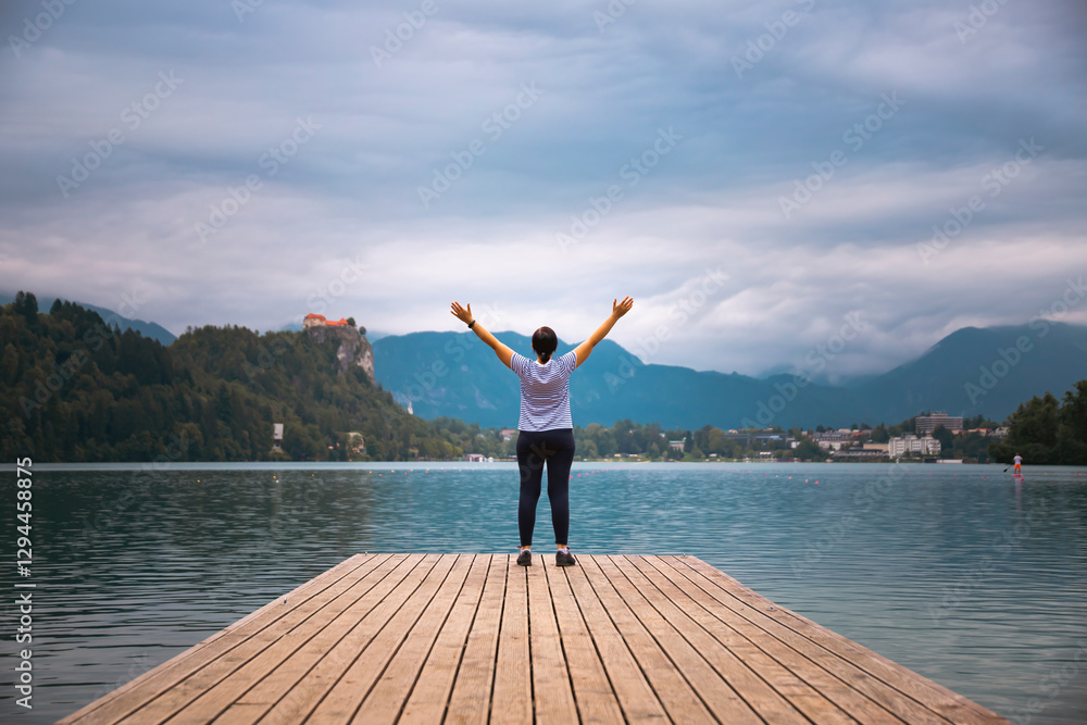 Woman standing on wooden deck, pier at Bled lake, Slovenia Woman standing on wooden deck, pier at Bled lake, Slovenia